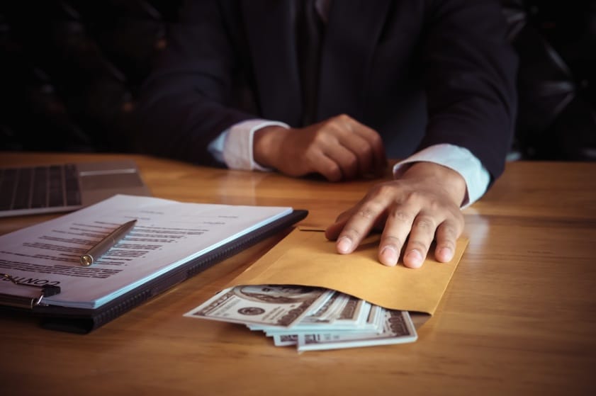 Bribe money in envelope being passed across table