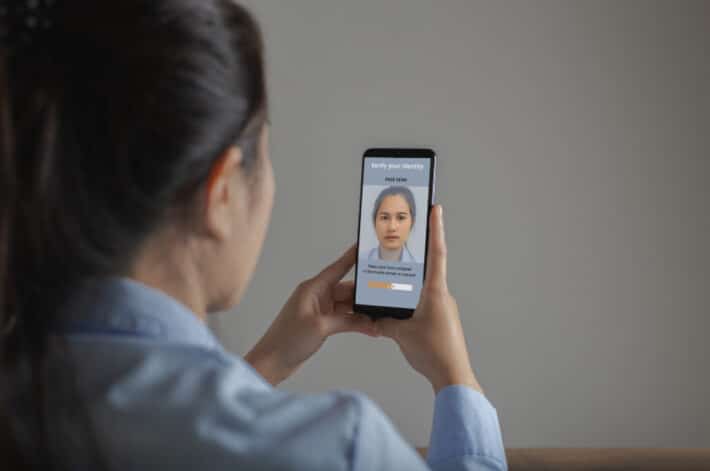 Asian woman scanning face with facial recognition system on smartphone